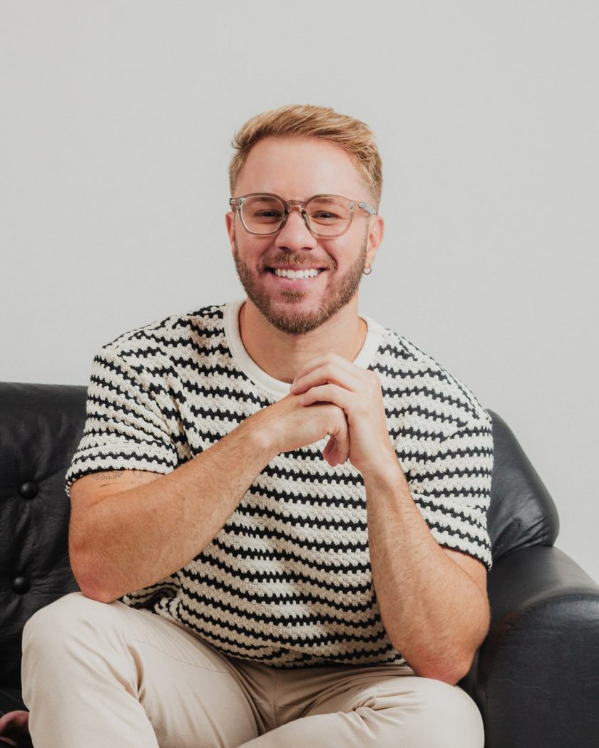 Rafael Figueiredo, psicólogo, sorrindo, sentado em uma poltrona